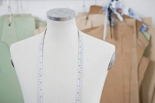 An armless mannequin with a measuring ribbon strung over it
