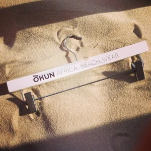 White Wooden Clothes Hangers, Printed With Logo - Okun Africa. Beach. Wear.